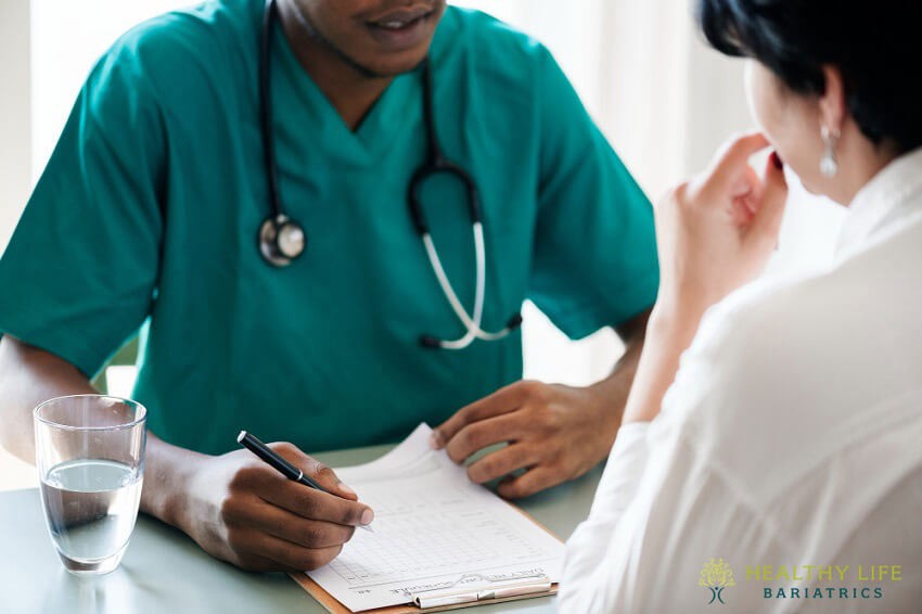 A doctor is talking to a patient at a desk.