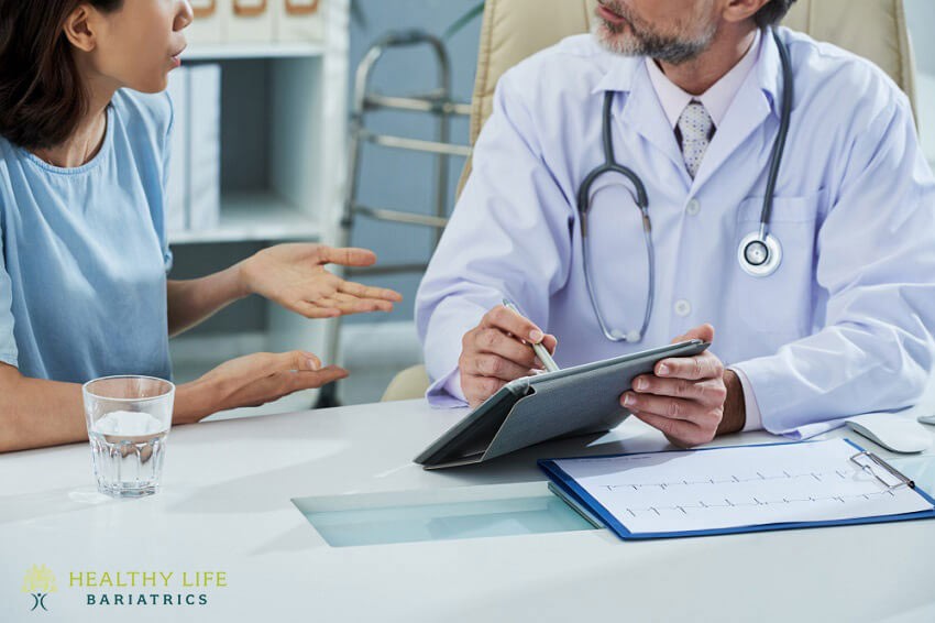 A doctor is talking to a woman at a desk.