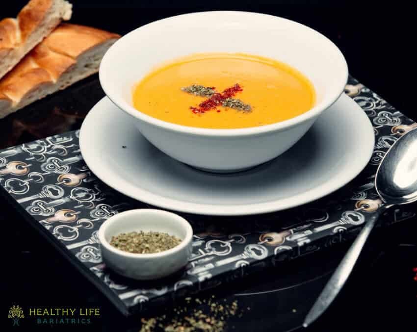 A bowl of soup with bread on a tray.