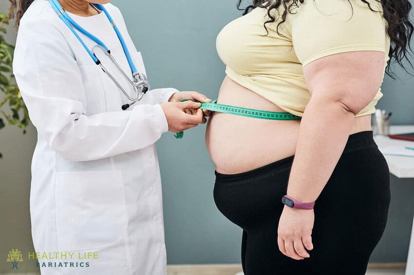 A woman is measuring her waist with a measuring tape.