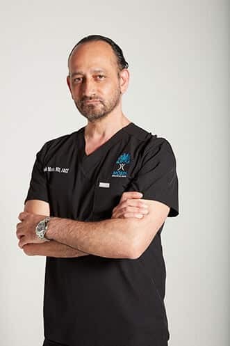 A man in black scrubs posing for a photo.