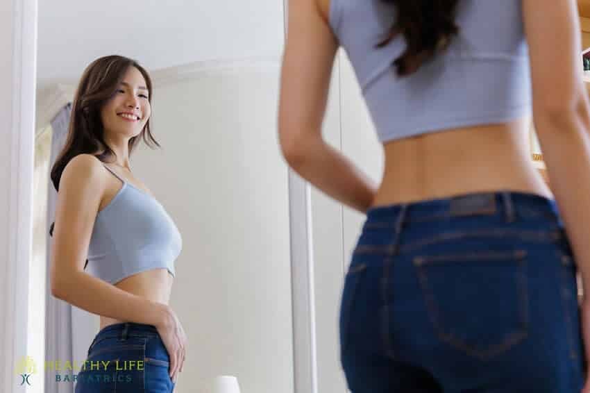 A woman is standing in front of a mirror.