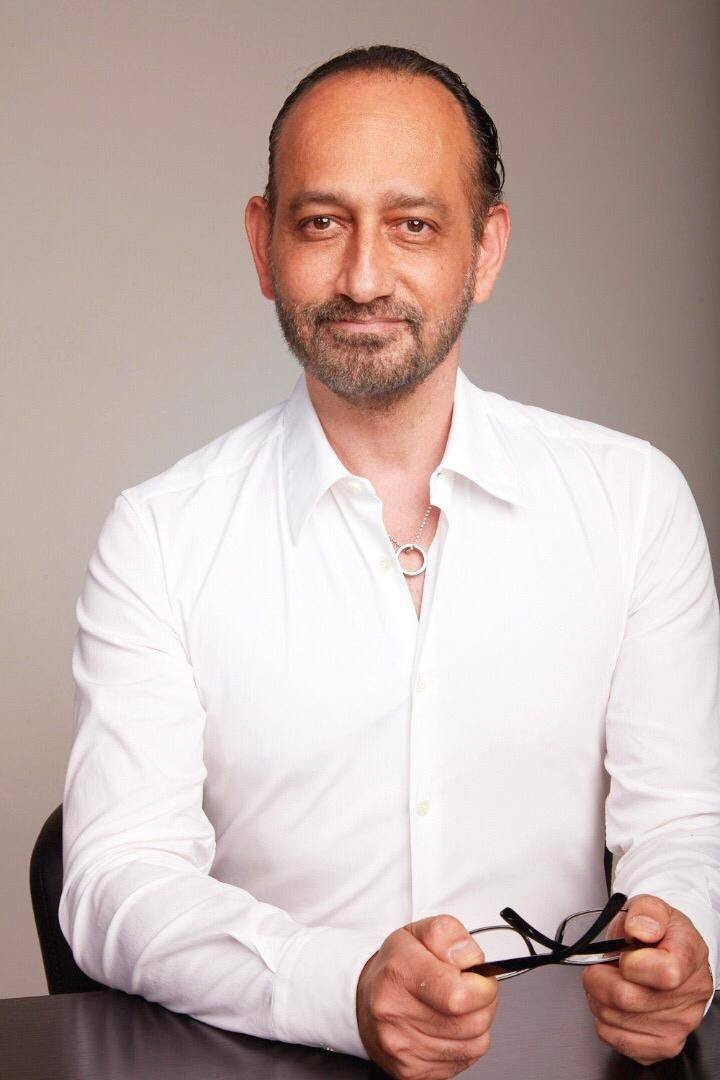 A man in a white shirt with glasses sitting at a table after weight loss surgery.