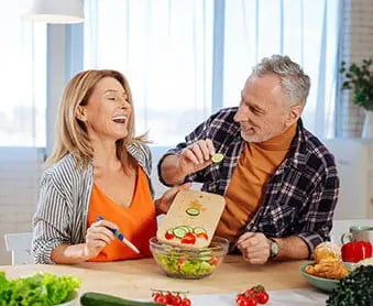 A couple undergoing weight loss surgery preparing a salad in the kitchen.