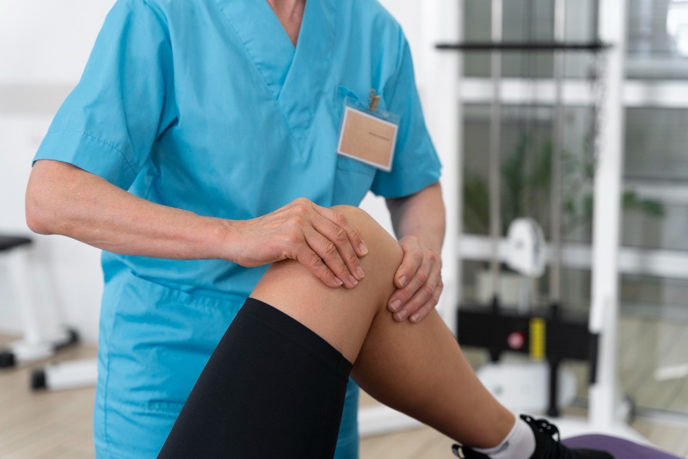 A woman is having her knee examined by a physical therapist, focusing on joint pain reduction.