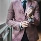 A man wearing a pink blazer and tie at an awards ceremony.