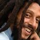 A man with dreadlocks smiling for the camera, showcasing his awards.