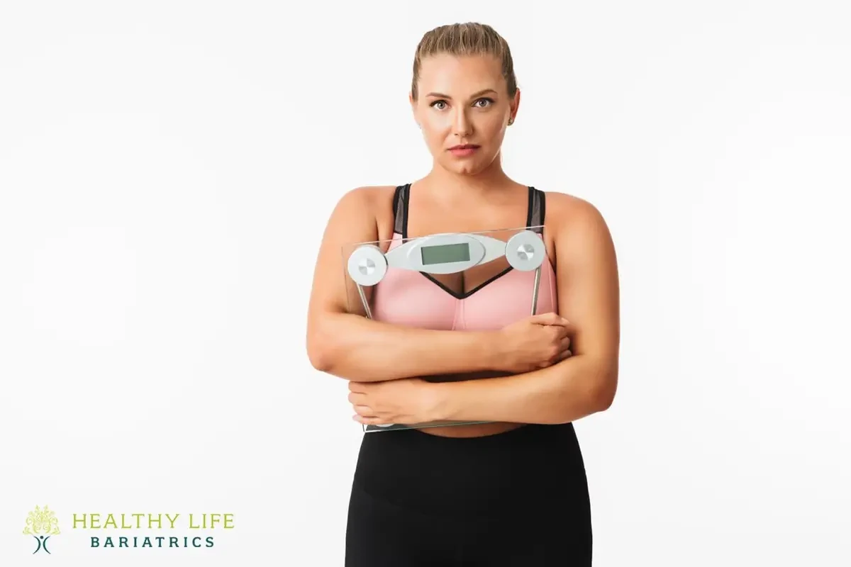 A woman holding a weight scale in front of a white background.