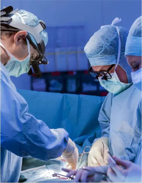 Surgeons in scrubs and headlamps perform weight loss surgery, focusing intently on their task in a well-lit operating room in Los Angeles.